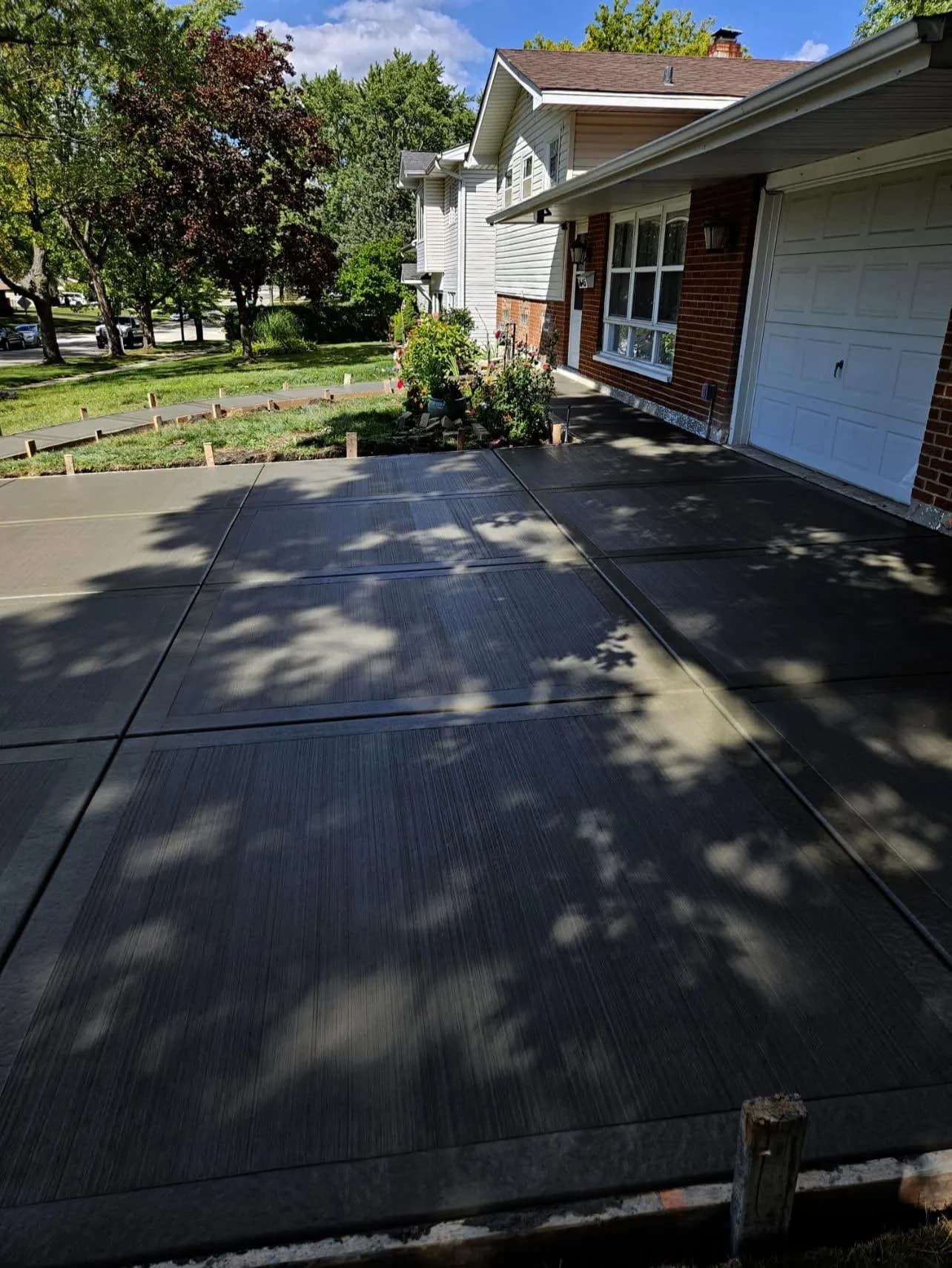 Broom-finish concrete driveway leading to a brick home by Ortiz Concrete Services