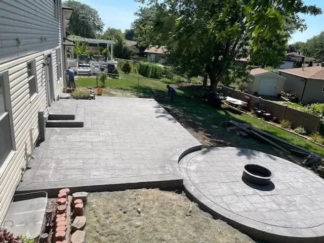 Stamped concrete patio with a circular fire-pit pad by Ortiz Concrete Services