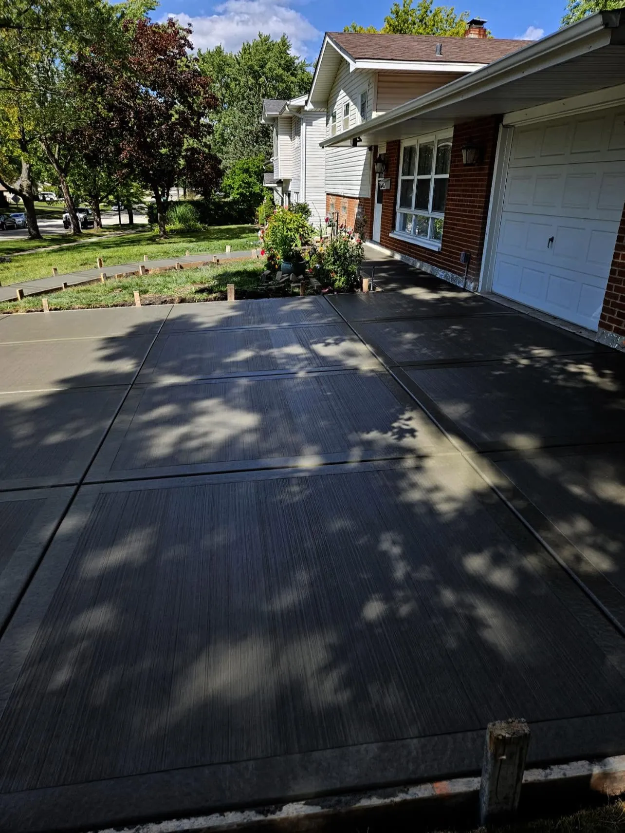 Broom-finish concrete driveway leading to a brick home by Ortiz Concrete Services