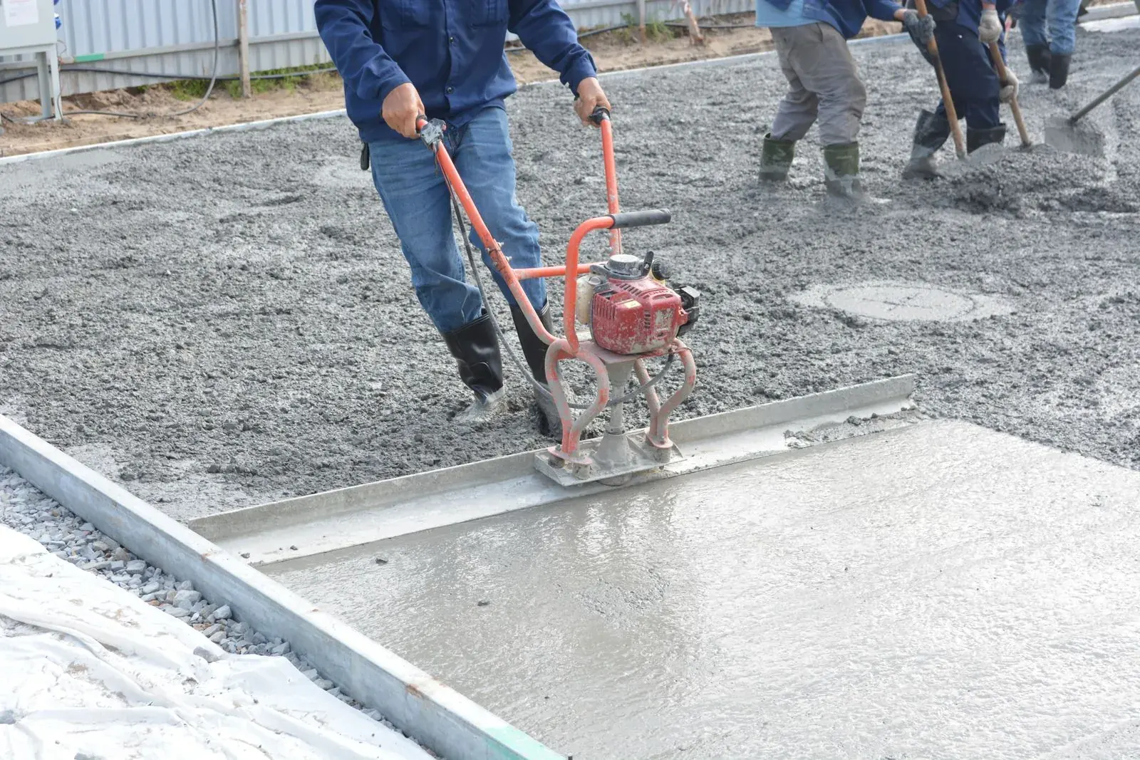 Crew screeding and leveling a freshly poured concrete slab by Ortiz Concrete Services