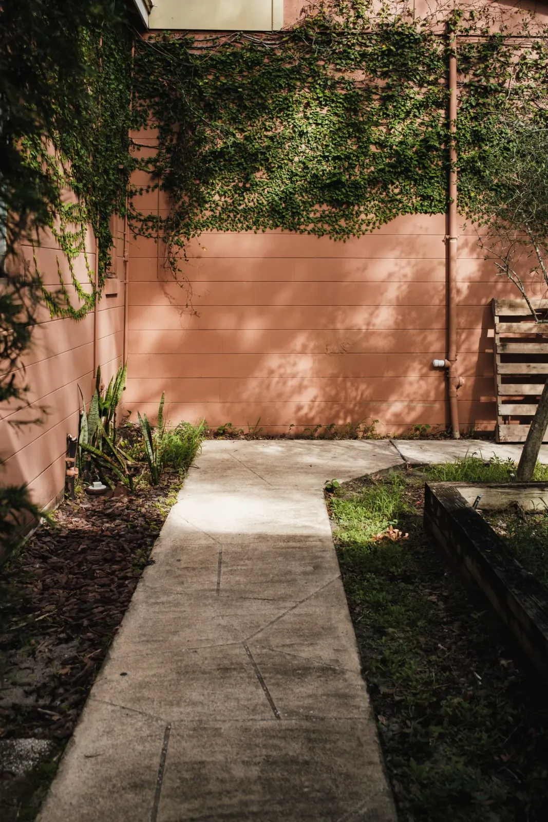 Poured concrete walkway with control joints leading through a landscaped residential yard by Ortiz Concrete Services